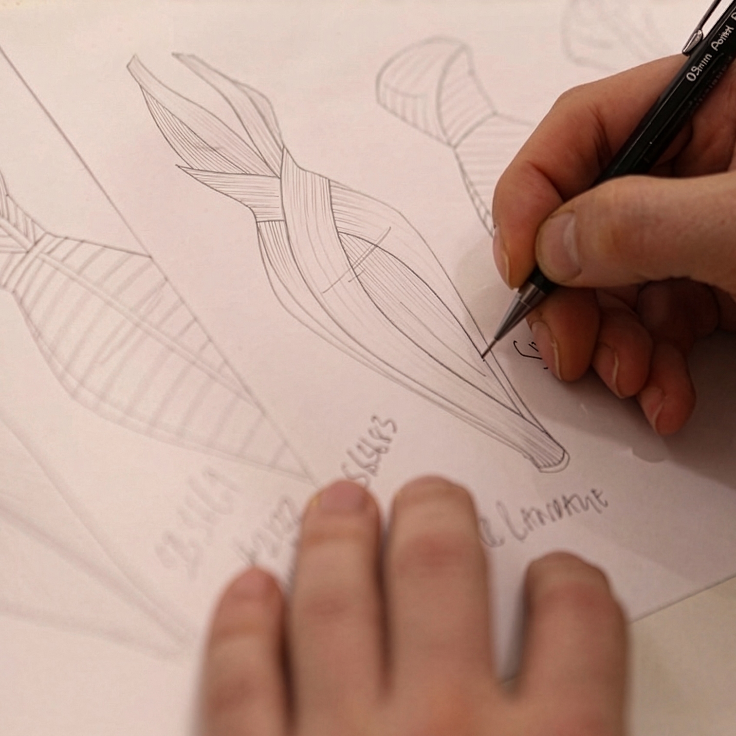 Designer's hands sketching a draped garment design in pencil on paper